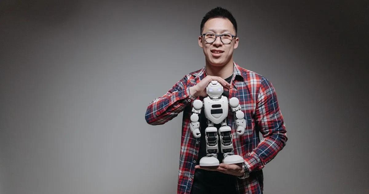 Man holding a miniature humanoid robot